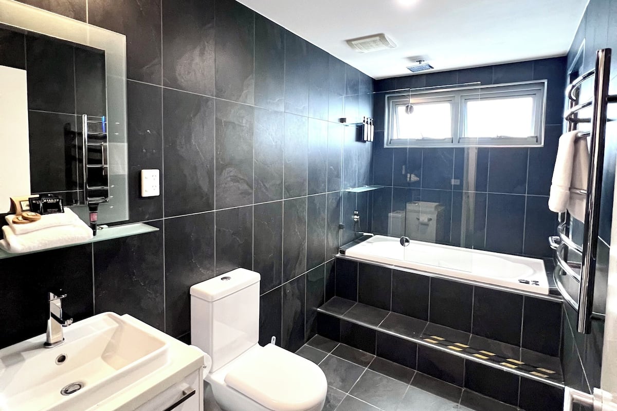 A modern bathroom with a toilet, sink, and bathtub.