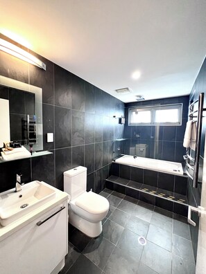 Ein modernes Badezimmer mit Toilette, Waschbecken und Badewanne.