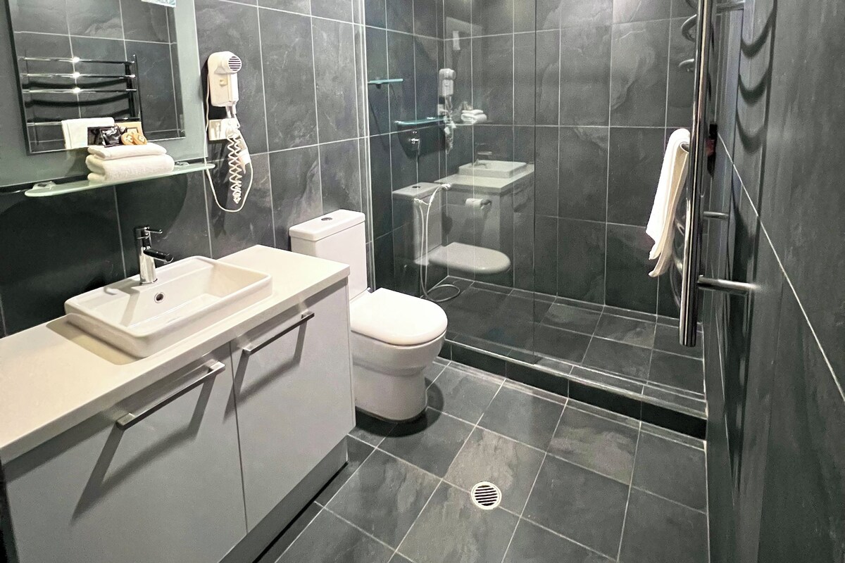 A modern bathroom with a glass-enclosed shower, a white sink, and a toilet.