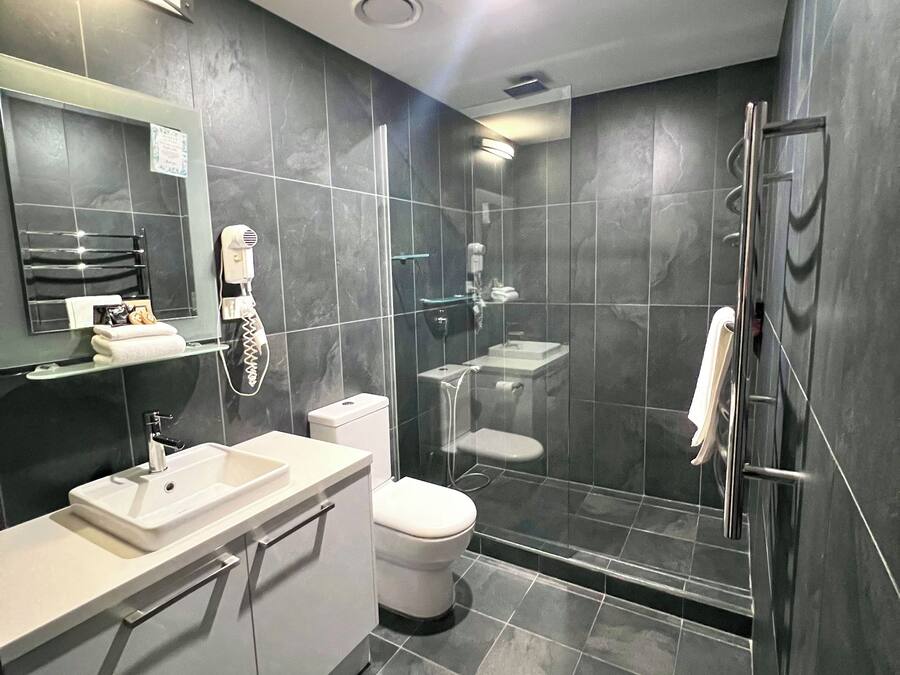 Un baño moderno con ducha de vidrio, lavamanos blanco y retrete.