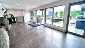 A spacious lobby with a reception desk, large windows, and a blue mat with "Crown on Darby" text. - Crown On Darby (Newcastle)