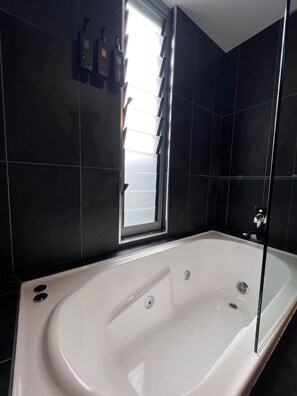 A modern bathroom with a freestanding bathtub, a window with blinds, and a shower area. - Crown On Darby (Newcastle)