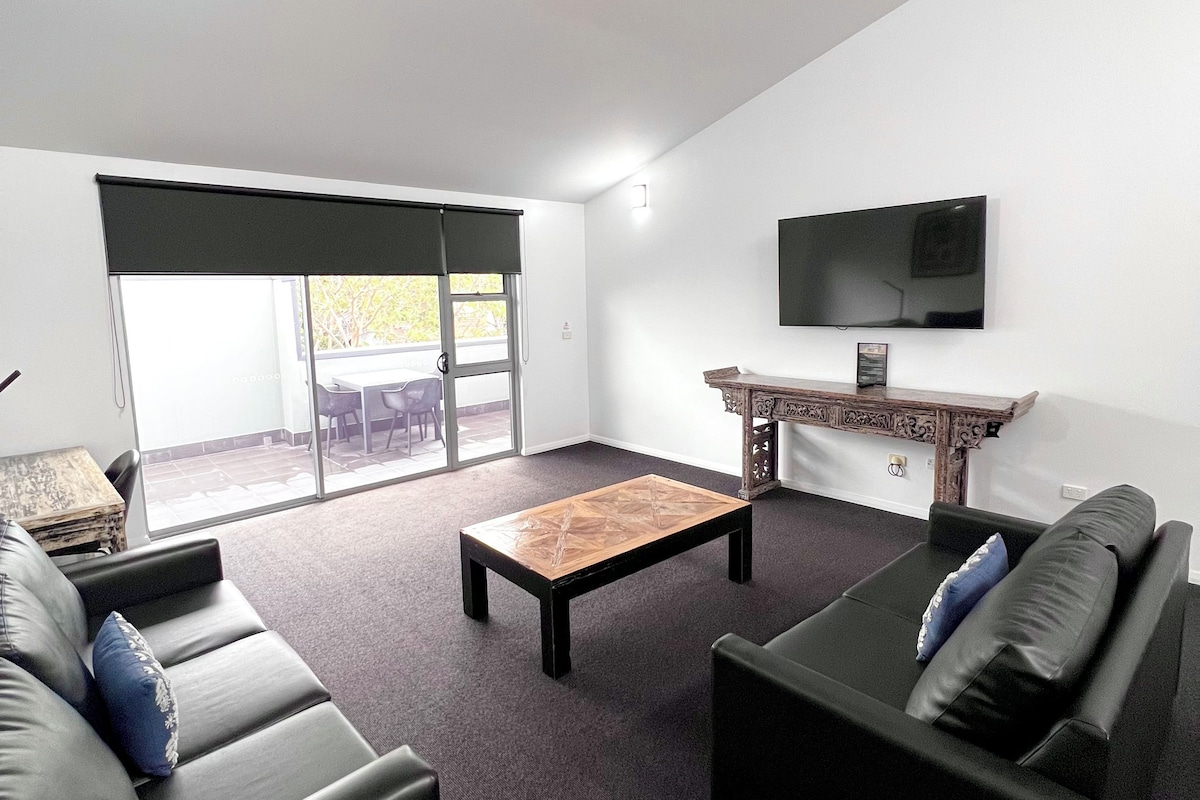 A modern living room with a sofa, a coffee table, and a TV.