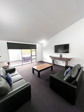 A modern living room with a sofa, a coffee table, and a TV. - Crown On Darby (Newcastle)