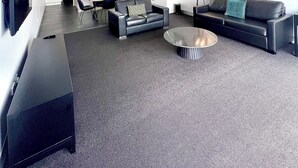 A modern living room with a sofa, a coffee table, and a dining area with chairs and a table.