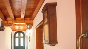 Un pasillo con vigas de madera, un reloj y una puerta con pomo de latón.