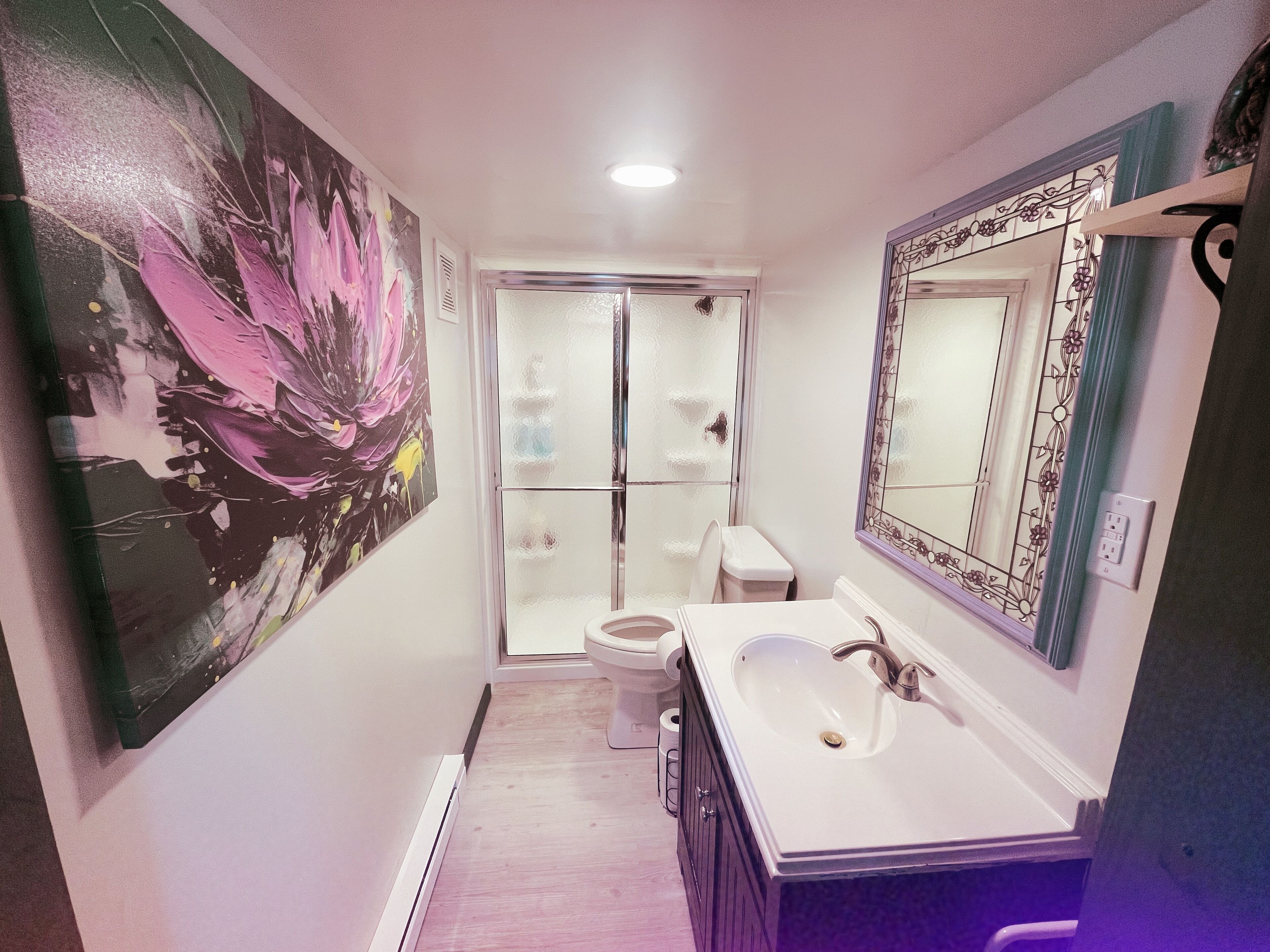 A bathroom with a large mirror, a sink, and a toilet.