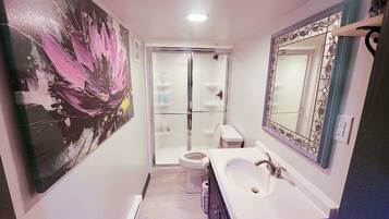 A bathroom with a large mirror, a sink, and a toilet.