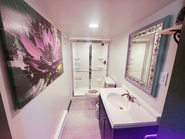 A bathroom with a large mirror, a sink, and a toilet.