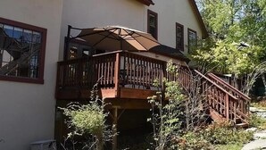 A two-story house with a wooden deck and a large umbrella. - Charming 4-bedroom Cabin in Peaceful Lake Arrowhead (Lake Arrowhead)