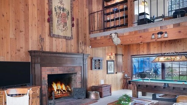 A spacious living room with a fireplace, a pool table, and a high ceiling with exposed beams. - Charming 4-bedroom Cabin in Peaceful Lake Arrowhead (Lake Arrowhead)
