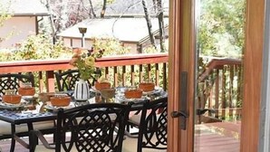 An outdoor dining area with a table set for two, surrounded by black chairs with a lattice backrest design. - Charming 4-bedroom Cabin in Peaceful Lake Arrowhead (Lake Arrowhead)