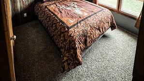 A bedroom with a bed, wooden walls, a window, and a ceiling light. - 3-bedroom cabin located in Steuben County home of 101 lakes! (Angola)