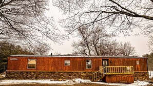A wooden cabin with a stone foundation, a front porch, and a chimney. - 3-bedroom cabin located in Steuben County home of 101 lakes! (Angola)