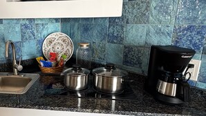 A kitchen with a sink, a coffee maker, and two pots on the stove. - Ocean Breeze Over Water Bungalow, 1 Bedroom, 1 Kingbed, 1 Living Room, 1 Kitchen (Bastimentos Island)