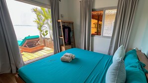 A bedroom with a bed, a wooden ladder, a window, and a view of an outdoor area. - Ocean Breeze Over Water Bungalow, 1 Bedroom, 1 Kingbed, 1 Living Room, 1 Kitchen (Bastimentos Island)