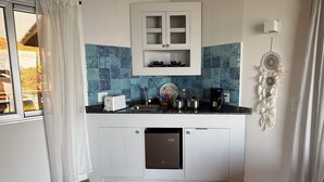 A compact kitchen with a white cabinet, a coffee maker, and a dreamcatcher on the wall. - Ocean Breeze Over Water Bungalow, 1 Bedroom, 1 Kingbed, 1 Living Room, 1 Kitchen (Bastimentos Island)