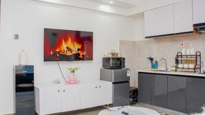 Une cuisine moderne équipée d’un téléviseur à écran plat diffusant une image de feu, d’un distributeur d’eau, d’un four à micro-ondes et d’un égouttoir à vaisselle.
