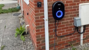 A brick building with a white door, a security keypad, and an electric vehicle charging station with a blue light. - Home Away From Home! Lovely House Near M1 (Nottingham)
