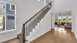 Un vaste espace de vie agrémenté d’un escalier en bois, de grandes fenêtres et d’une vue sur l’extérieur.