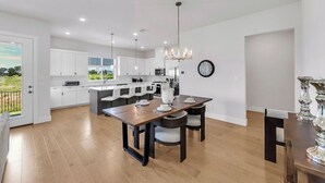 Une cuisine moderne avec des meubles blancs, un îlot central et des luminaires suspendus.