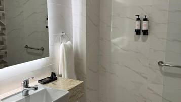 A modern bathroom with a marble sink, a large mirror, and a shower area.