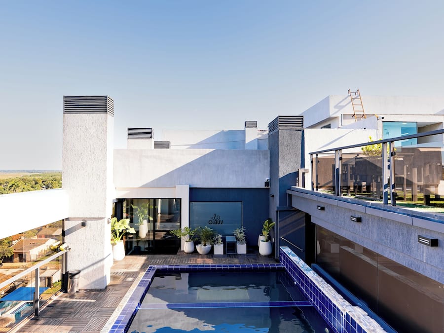 Una piscina en la azotea con vistas despejadas de los edificios circundantes y una terraza de madera.