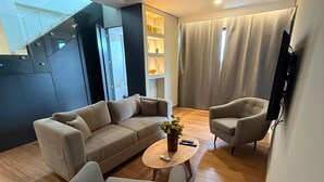 A modern living room with a sectional sofa, a round coffee table, and a TV mounted on the wall.