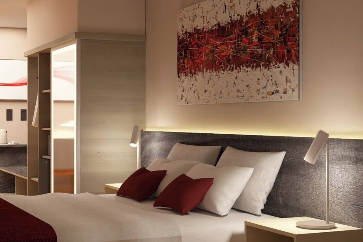 Quarto moderno com uma cama grande, mesa de cabeceira, escrivaninha e pintura pendurada na parede.