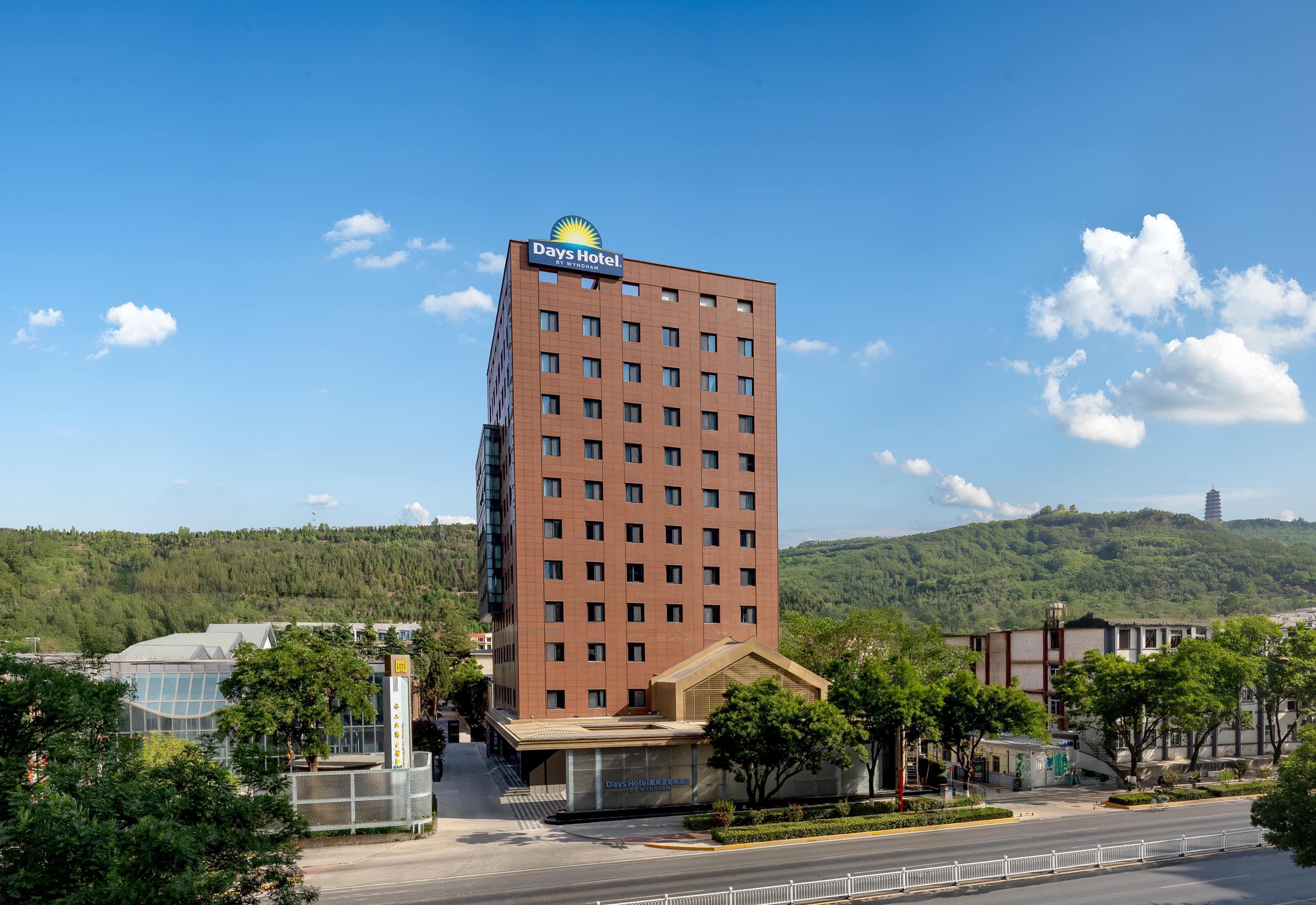 A Days Hotel building with a modern design, featuring a prominent sign at the top, a flat roof, and a large glass facade.