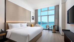 Una habitación de hotel moderna con una cama grande, un escritorio, una silla y un televisor.