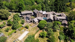 An aerial view of a rural property with multiple stone buildings, surrounded by dense forest. - Cosy gîte with view, jacuzzi & pool - heart of the Cévennes, hiking, relaxation. (Ventalon en Cévennes)