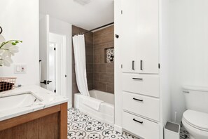 Un baño moderno con un lavamanos blanco, una bañera y un inodoro.