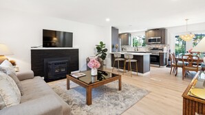 A modern living room with a fireplace, a dining area, and a kitchen.