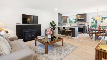 A modern living room with a fireplace, a dining area, and a kitchen.
