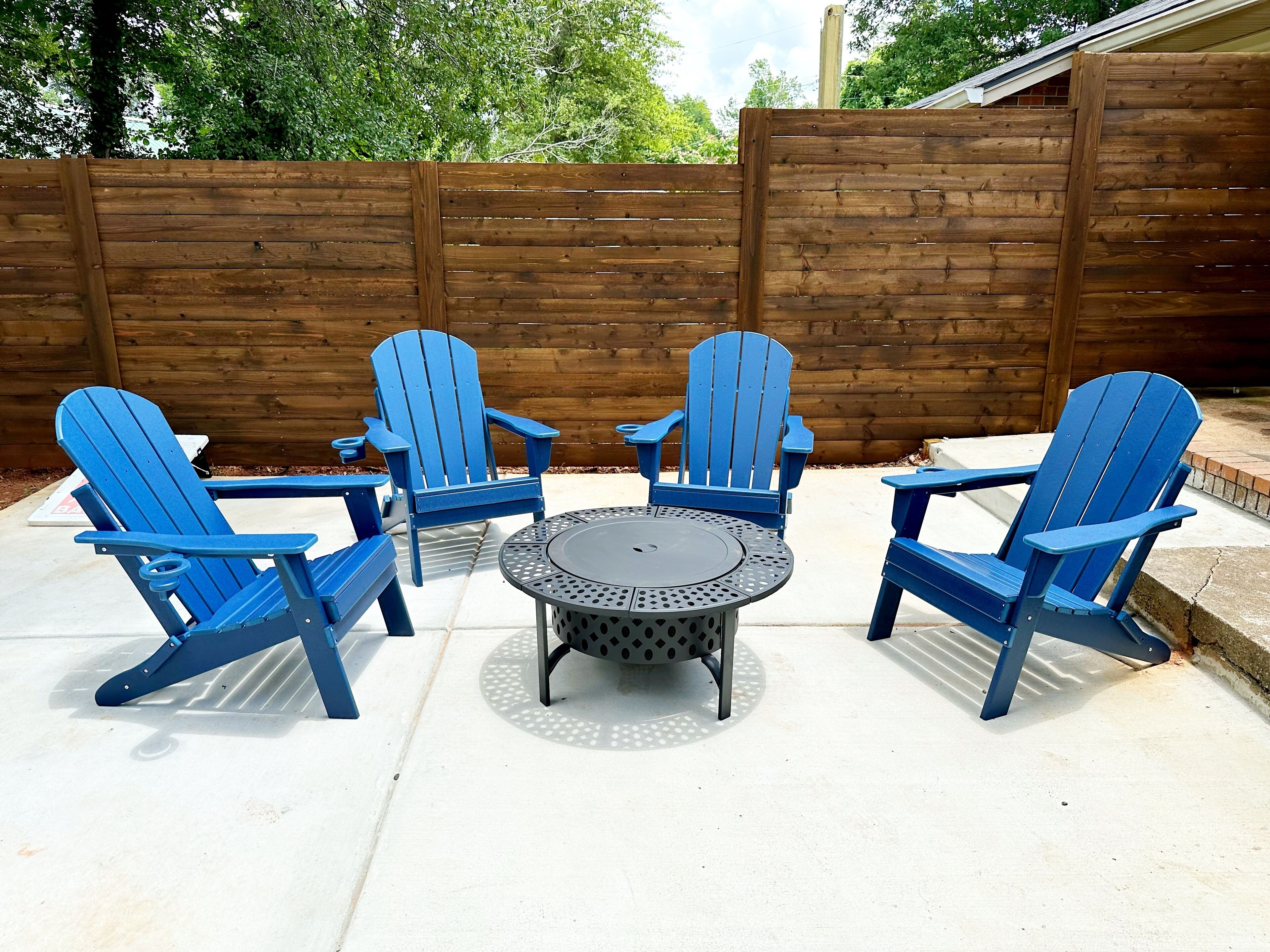 A patio with four blue Adirondack chairs and a round table.