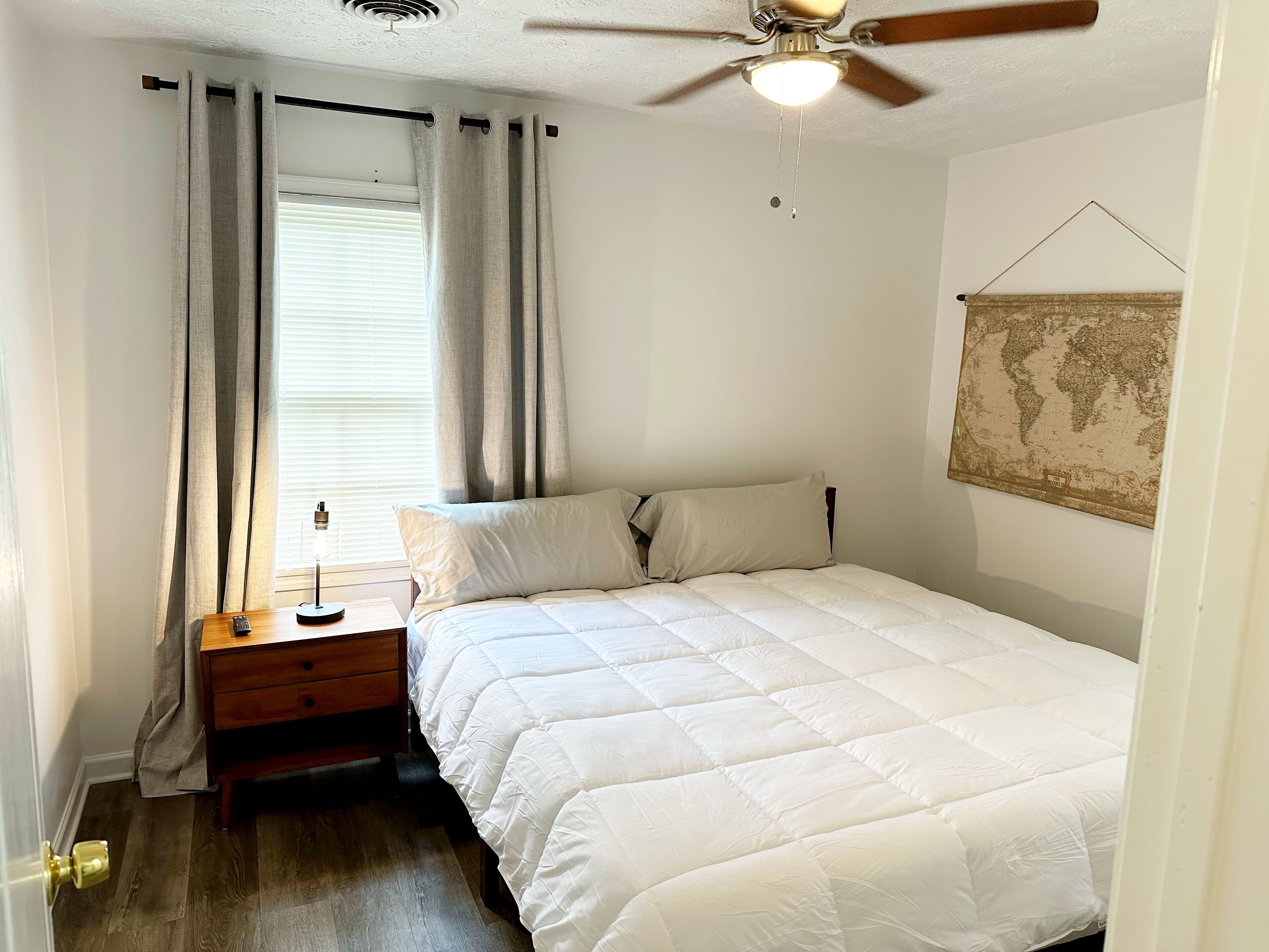A bedroom with a bed, a nightstand, a globe on the wall, and a ceiling fan.