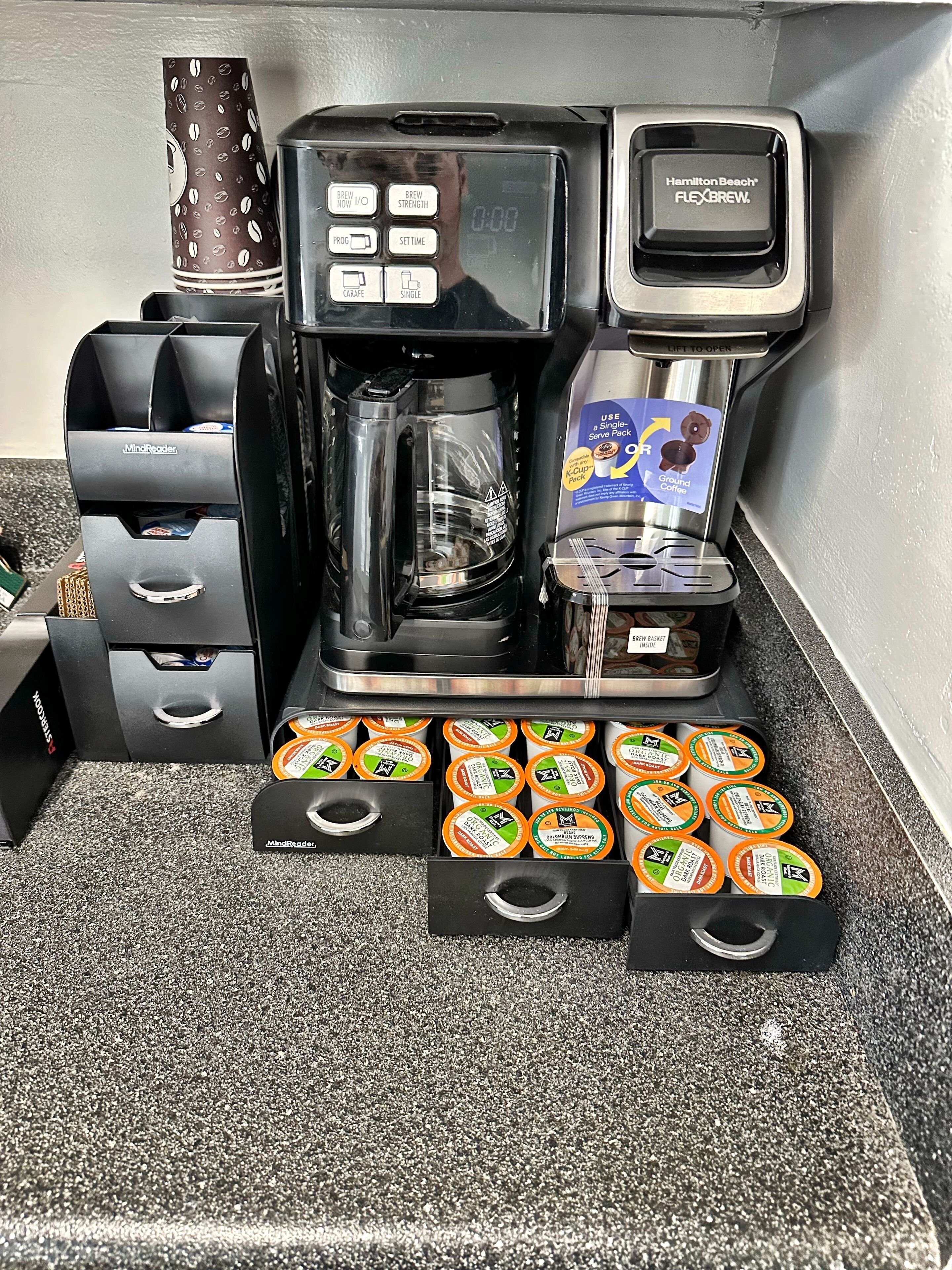 Une machine à café dotée d’un écran numérique, d’un moulin à café et d’un compartiment pour capsules de café, pouvant en contenir plusieurs.
