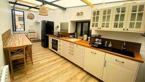 A modern kitchen with wooden flooring, a dining table, and white cabinets. - CHEZ MIMI - Holiday home (Jard-sur-Mer)