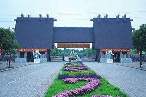 A building entrance with a paved pathway leading to it, flanked by two large gates.