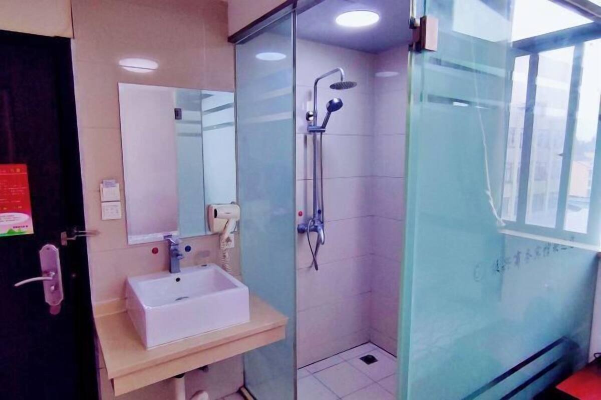 Een badkamer met een glazen douchecabine, een wastafel met spiegel en een zeepdispenser.