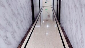 Un couloir aux murs recouverts de marbre, doté d’un sol réfléchissant et d’une bande noire qui le traverse au centre.