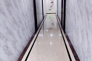 A marble-lined hallway with a reflective floor and a black border.