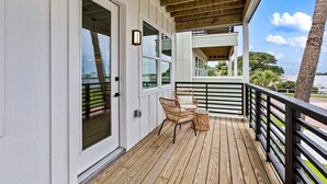 Une terrasse en bois avec une rambarde, une chaise en osier et une petite table.