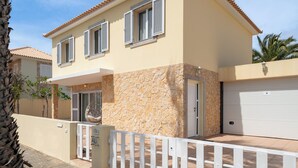 A two-story house with a stone facade, a white garage door, and a white fence. - With outdoor space - Moradia Felicidade Rocha PXO (Lombas)