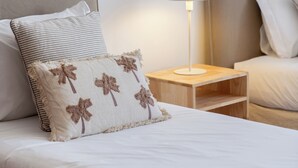 A neatly made bed with a striped pillow and a floral pillow, a bedside table with a lamp, and a headboard. - Quebra Costas I – A Refuge with Panoramic Views (Funchal)