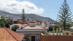 A coastal town with terracotta-roofed buildings, a prominent church, and a mountain backdrop. - Quebra Costas I – A Refuge with Panoramic Views (Funchal)