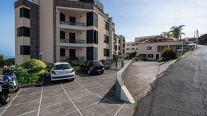 Un immeuble d’appartements moderne doté de nombreux balcons, d’un espace de stationnement et offrant une vue sur la mer.