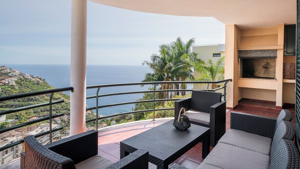 Un balcon avec coin salon extérieur, une cheminée et une vue sur l’océan.