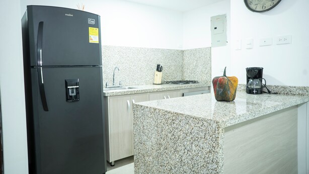 A kitchen with a black refrigerator, granite countertops, a sink, a stove, and a clock on the wall. - Apartment 5B Minaret (Bolívar)
